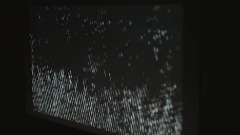 a single computer monitor screen flashing a strobing static noise pattern in a dark room