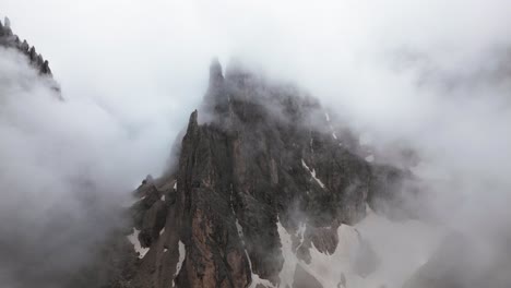 steep rock face with clouds and snow in the mountains, dolomites, italy, europe, drone