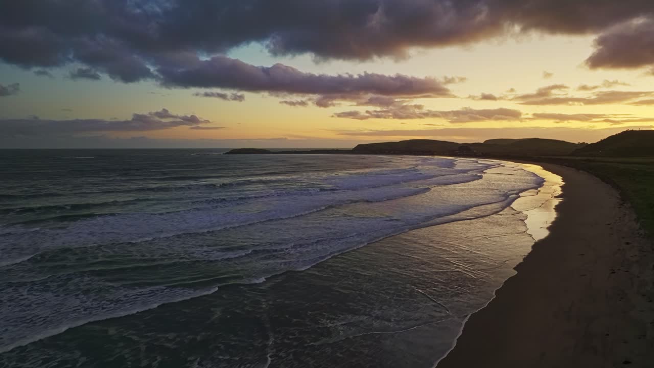 establecimiento aéreo panorámico de la luz del anochecer sobre la hermosa bahía costera con largas olas