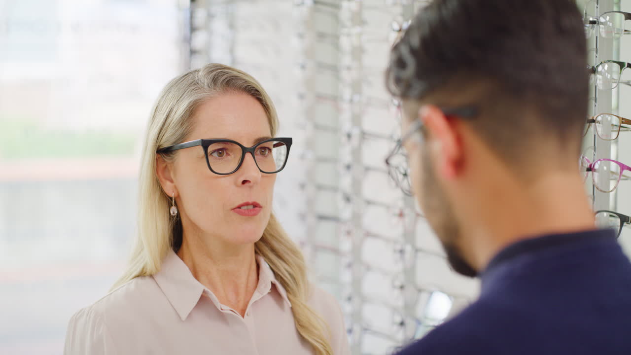 Woman checking sight of man buying glasses