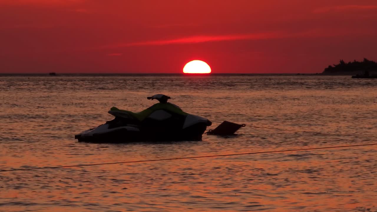 ⁇  스키가 평온한 바다 표면에 떠다니며 해가 지는  ⁇ 은 하늘을 반영합니다. 해가 바다 지평선에서 반 ⁇  내려오고 있습니다. 여름 휴가입니다.