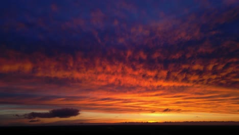 altocumulus puesta de sol naranja con nubes en forma de cumulus cielo azul y suelo negro
