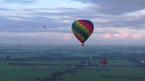 Vista-Aérea-Del-Colorido-Globo-Aerostático-Volando-Sobre-La-Pradera,-Países-Bajos