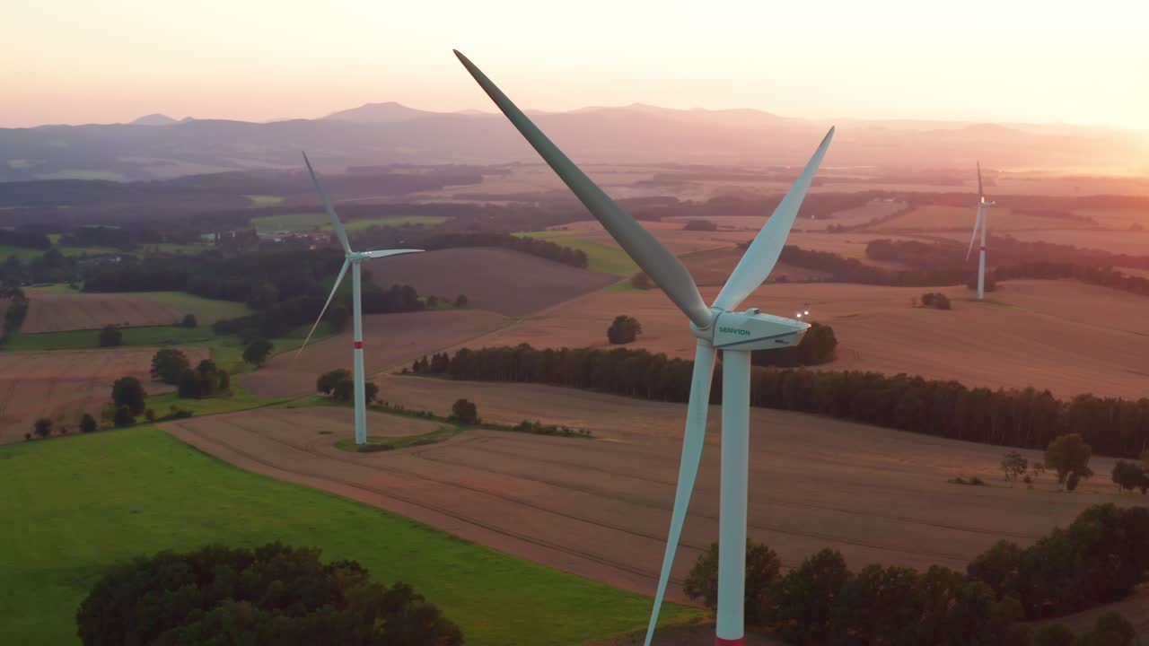 Windmills operate at sunset producing renewable energy