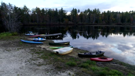 fast panning drone shot of empty boats and canoes on the shore of a beautiful pond