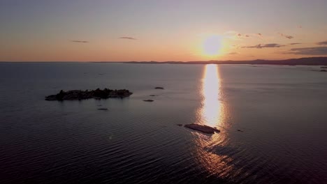 Pequeñas-Islas-Rocosas-En-Un-Gran-Lago-Azul-Al-Atardecer,-Una-Amplia-Plataforma-Aérea-De-Drones-En