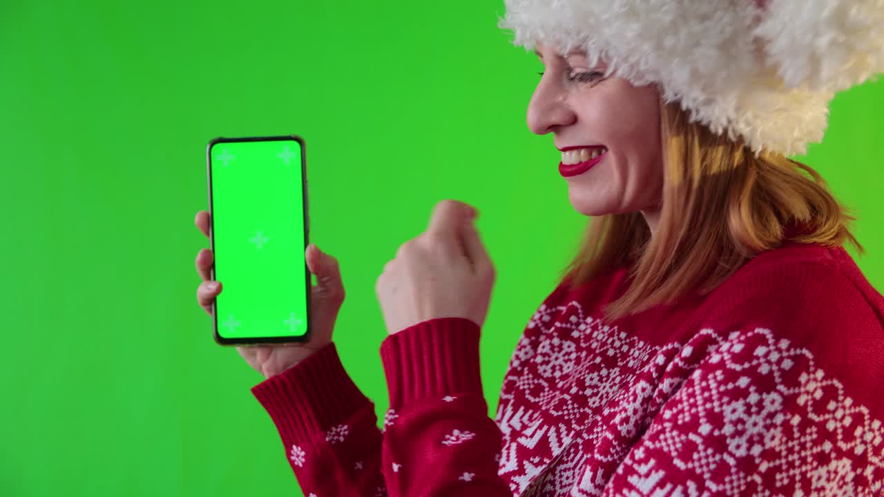 una mujer sonriente muestra un teléfono con pantalla verde.
