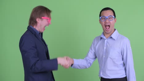 dos hombres de negocios nerds que se dan un apretón de manos contra el fondo verde del estudio.