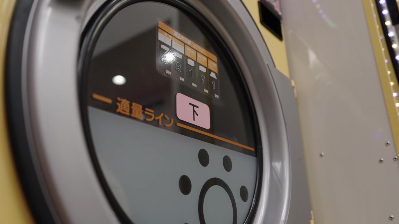 Closeup of laundromat washing machine glass door with japanese load level instructions