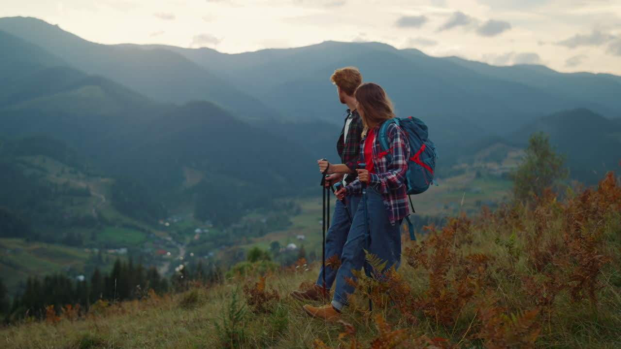 Sporty couple trekking in picturesque mountain. Family hiking travel on hill