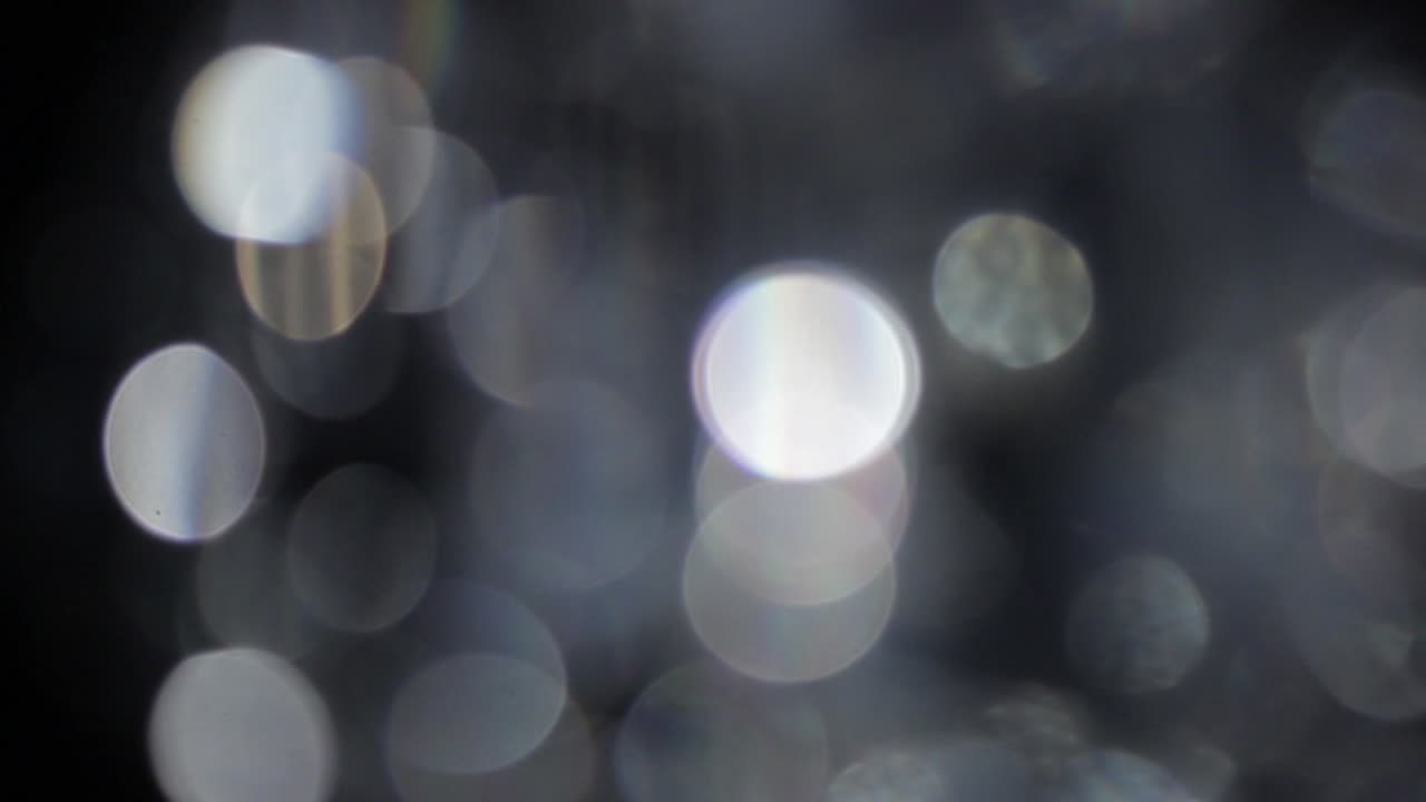 Particelle astratte di bolle bokeh luminose che volano su sfondo nero.