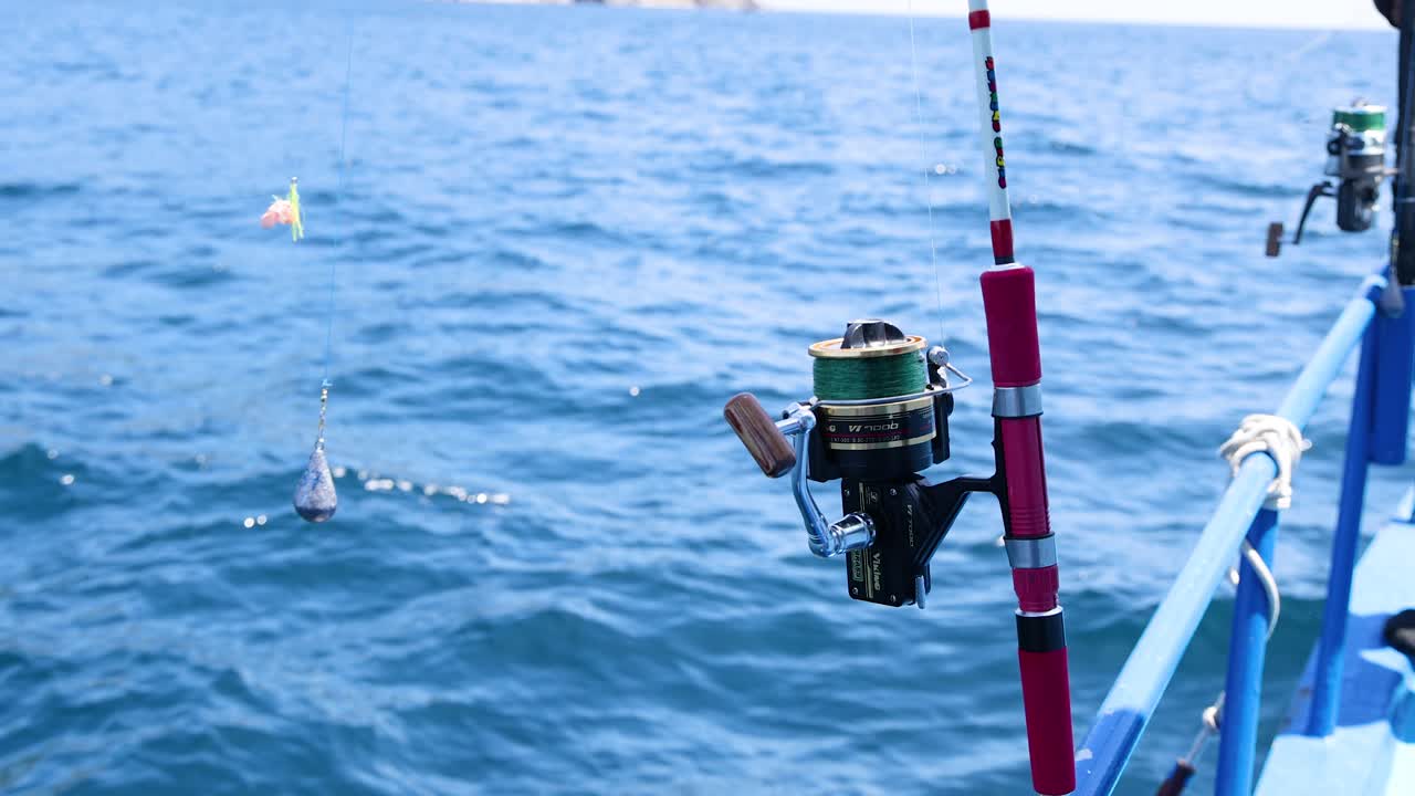 una caña de pesca en un barco en phuket, tailandia, captura el ambiente sereno del océano con olas suaves y luz del día brillante