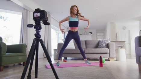 woman performing exercise at home and recording it with digital camera