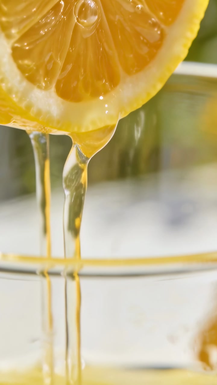 Fresh Lemon Juice Dripping from a Slice into a Glass