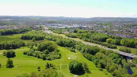 aerial video flying over a green golf course and crossing a freeway with a lot of car traffic