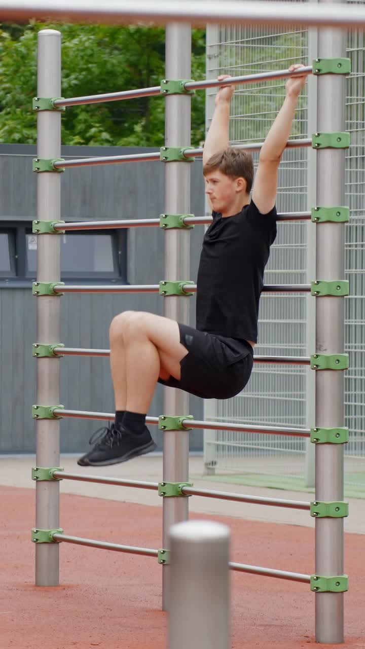 Person hangs, pulls up legs on outdoor gym bars, fitness exercise