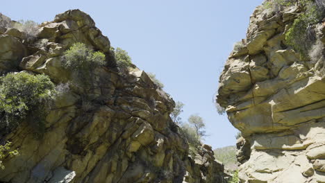 Descending-shot-of-ravine-between-two-large-boulders-located-in-Santa-Paula-Punch-Bowls-Southern-California