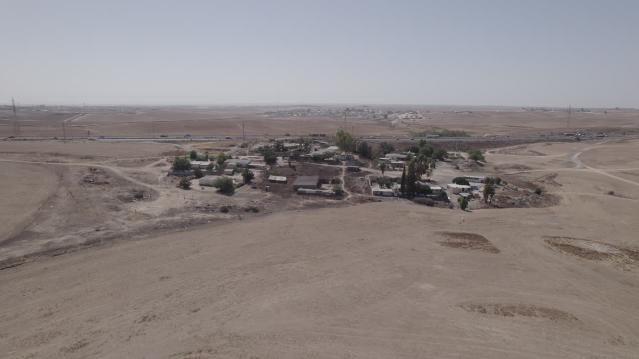Fotografia parallasse di case senza permesso in un'area remota e desertica, vicino a un'autostrada, con terreno arido e senza colture