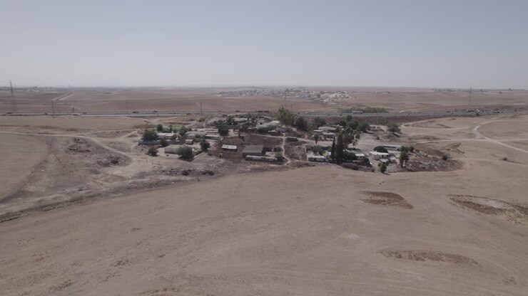 Fotografia parallasse di case senza permesso in un'area remota e desertica, vicino a un'autostrada, con terreno arido e senza colture