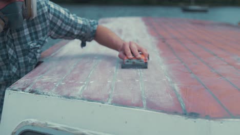 Hand-sanding-wooden-boat-wheelhouse-cabin-roof-planks,-SLOW-MOTION