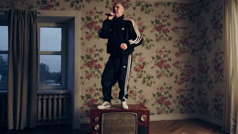 man singing on top of an old tv in a vintage room