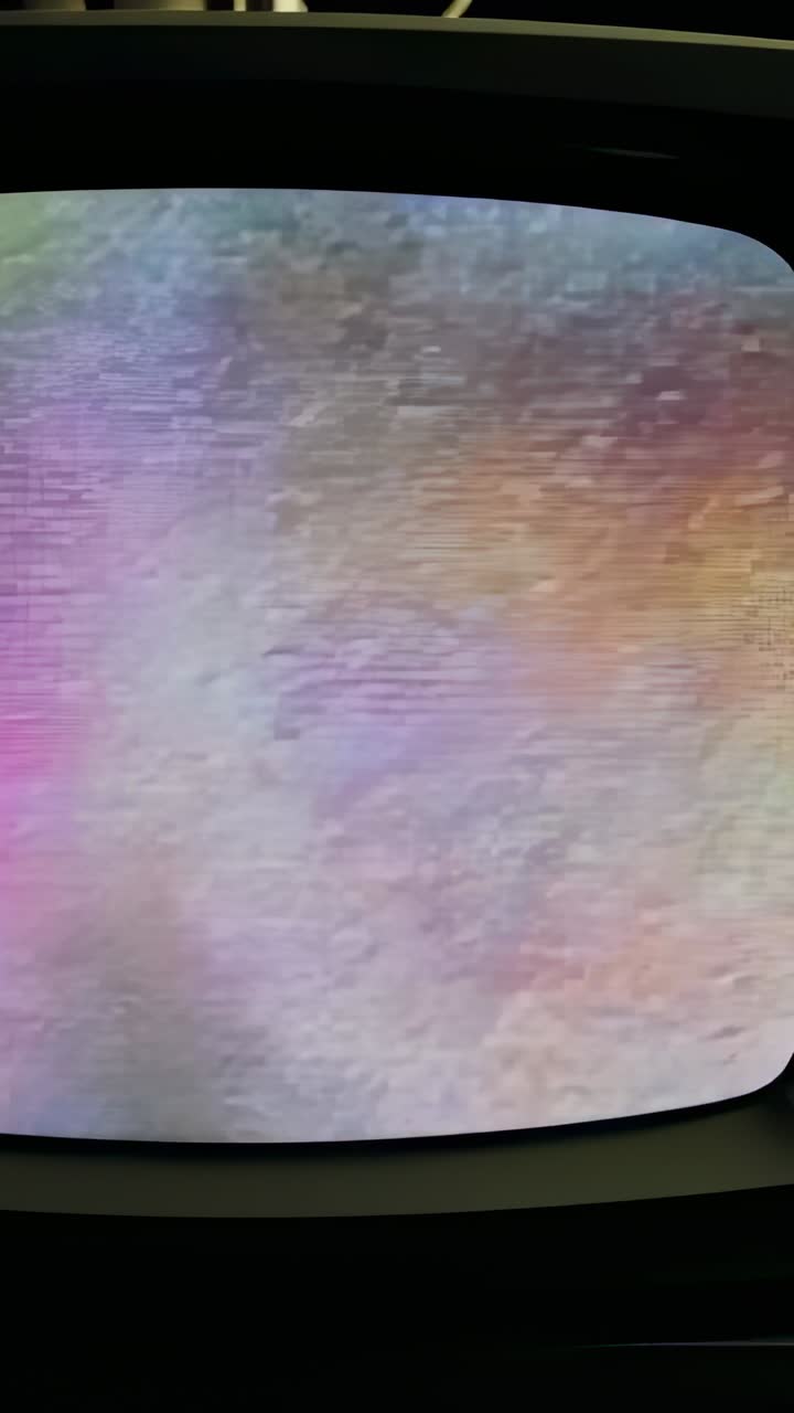 Vertical video: Receiving signal, curved monitor showing pink to blue static in room with bezel