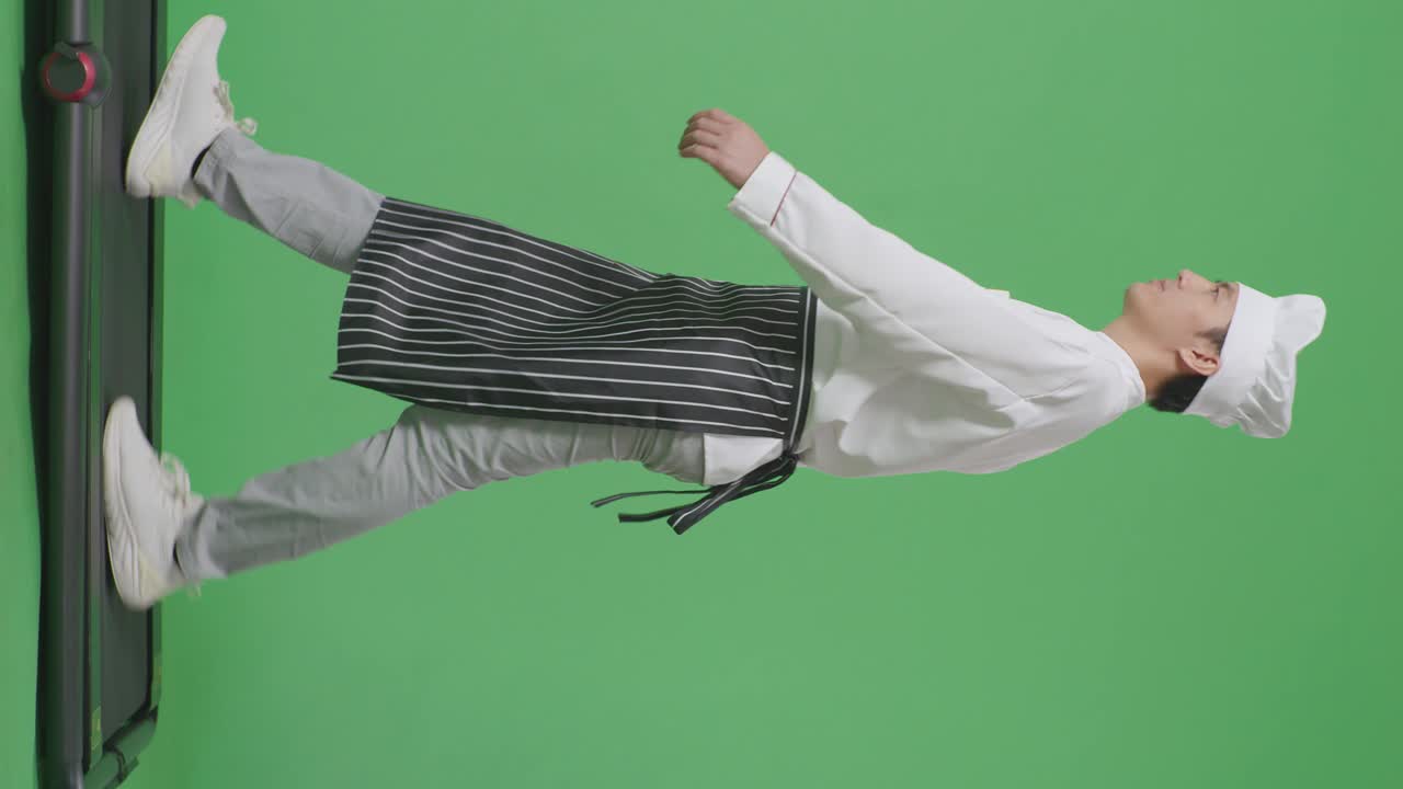 으로 보이는 몸으로 가득 찬 아시아 남성 요리사가 녹색 스크린 배경 스튜디오에서 트레드밀을 고 있습니다.