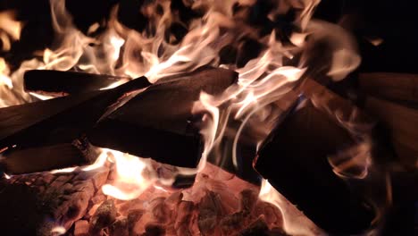 Hoguera-Con-Combustible-De-Madera-Quema-Rápidamente-Emitiendo-Calor-Y-Luz,-Brasas-En-El-Fondo,-Primer-Plano-Bloqueado-En-La-Oscuridad-De-La-Noche,-Galicia,-España