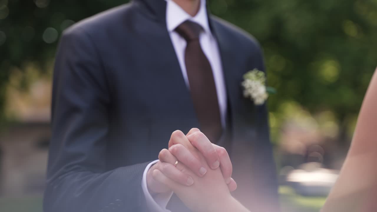 Bride and groom gently touching hands in a romantic wedding moment outdoors