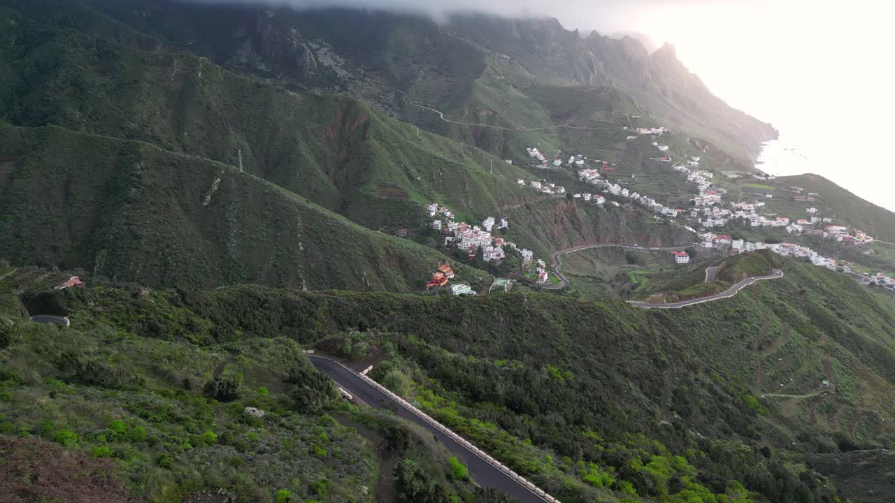 hermosa vista aérea de varios pueblos entre las verdes montañas de tenerife con el mar de fondo al atardecer