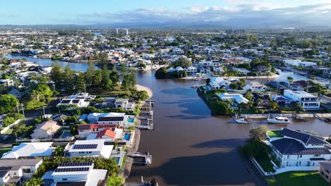 drone footage captures scenic river and residential area in gold coast, australia, under clear skies with vibrant lighting