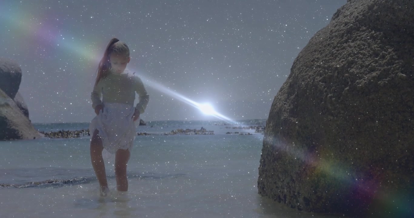 Un bambino che guada nell'acqua costiera sollevando la gonna per non bagnarsi, avvicinandosi a un masso in una scena di viaggio.