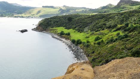 Aerial-view-of-idyllic-Kauri-Coast-during-bright-sunny-day-with-green-mountains-and-rocky-shoreline