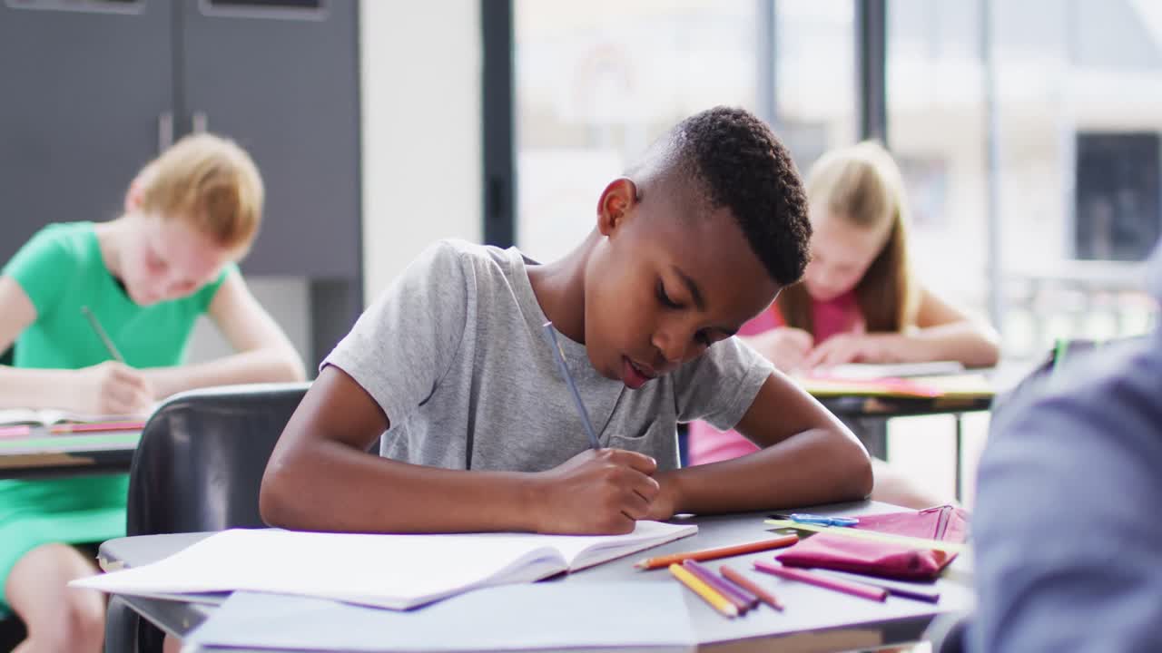 Portrait of happy diverse schoolchildren at desks in school classroom