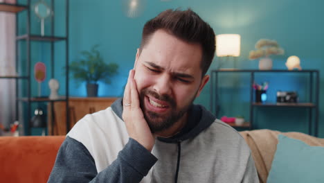 young caucasian man touching cheek, suffer from terrible painful toothache, sensitive teeth cavities