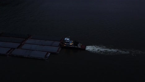 a barge pushing large shipping containers up the hudson river in new york's hudson valley just after sunset