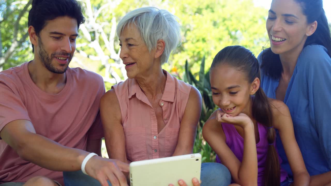 familia mirando la tableta digital en el parque 4k