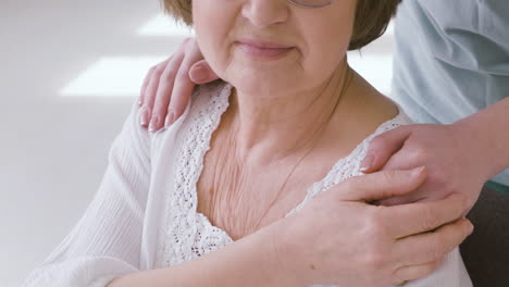 anciana sentada en un sofá y doctora poniendo las manos sobre sus hombros 1