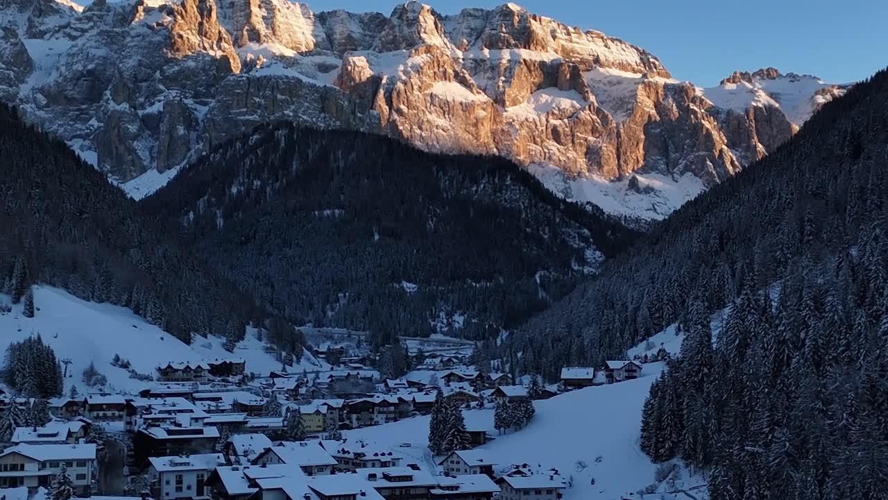 Snow-covered village in the Alps under golden mountain sunlight in Italy