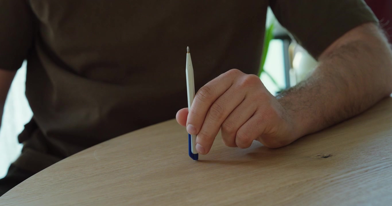 Человек стучит ручкой по столу, демонстрируя нервное поведение, стресс и беспокойство в непринужденной обстановке