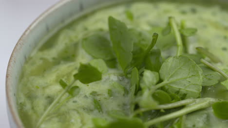 watercress soup rotating in blue bowl with white background. healthy lunchtime recipe.protein plant based raw vegan food. health and vegetarian foods. healthy ingredients. 4k macro food shot