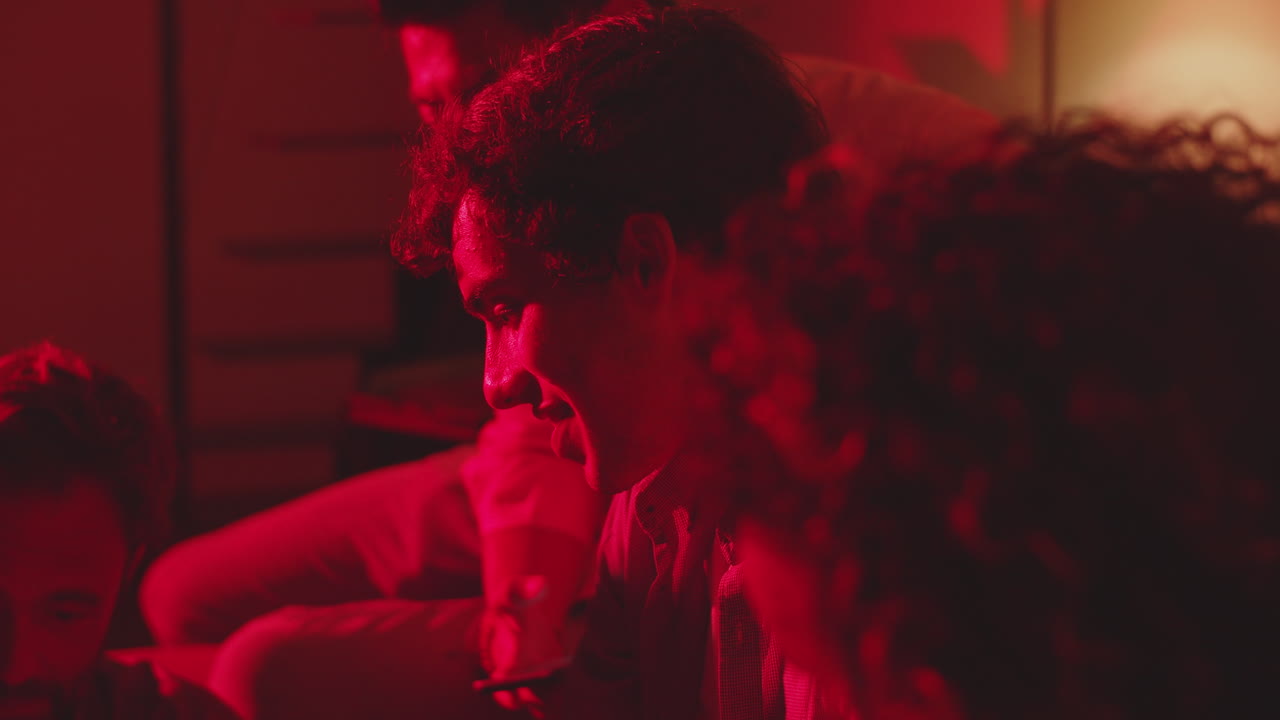 grupo de amigos hablando en una habitación oscura con una cálida luz roja