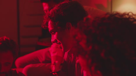 group of friends talking in dark room with warm red light