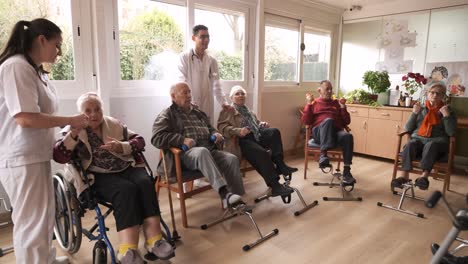 male doctor controlling aged people exercising with bike pedals
