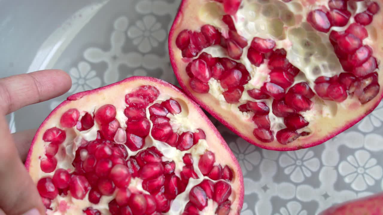 Opening red pomegranate splitting open with seeds inside pulp and nice juicy flavor healthy anti-oxidants cardioprotective properties
