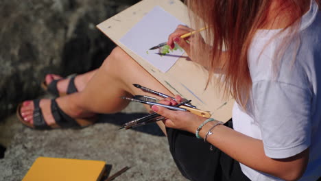 woman painting outdoors on rocks