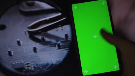 the green screen is a smartphone, and in the background is the it hardware motherboard and chip activities