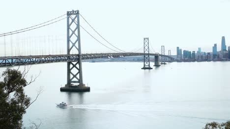 cars passing by the bay bridge and boat sailing by the bay