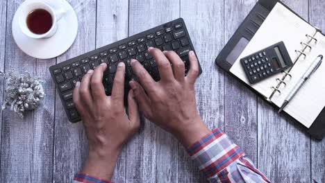 person typing on a keyboard at a desk with other office supplies