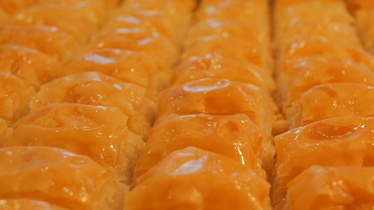 baklava turca fresca de color dorado. dolly disparando baklava que está en filas pares en una hoja de horneado. tradicional postre nacional turco. ramadán